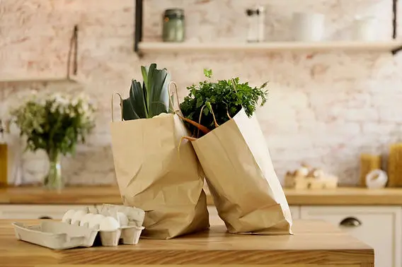 2 sacs de courses en papier posés sur un ilot de cuisine.