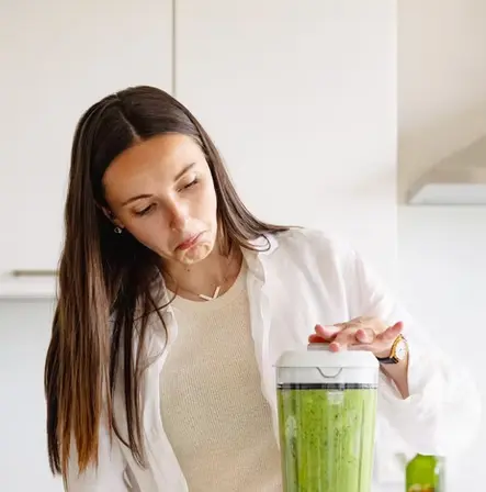Une jeune fille aux long cheveux bruns en train de préparer du pesto vert