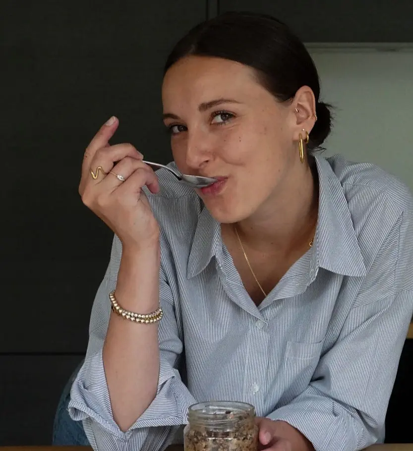 Une femme aux cheveux bruns attachés en train de manger